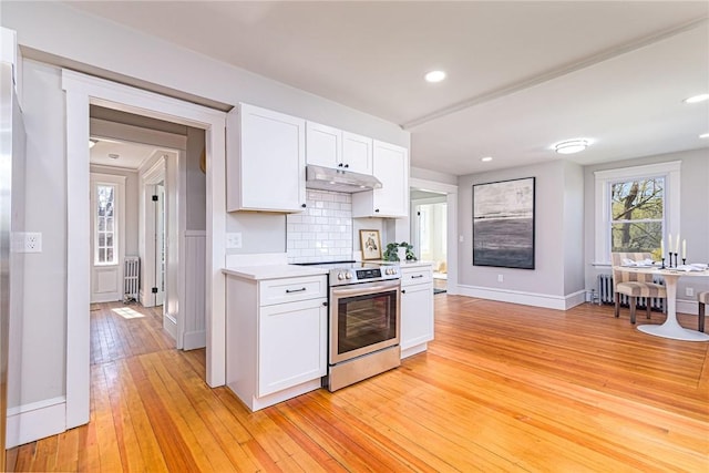 888 Providence St, West Warwick, RI 02893 - kitchen with electric range, light countertops, white cabinets, under cabinet range hood, and light wood-style flooring