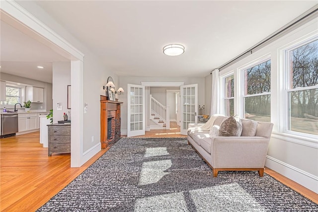888 Providence St, West Warwick, RI 02893 - living room featuring baseboards, a fireplace, french doors, and light wood-type flooring