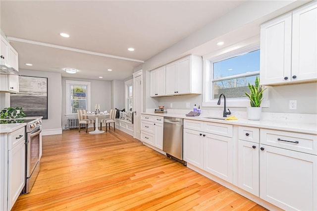 888 Providence St, West Warwick, RI 02893 - kitchen with white cabinets, stainless steel appliances, a sink, and light wood finished floors