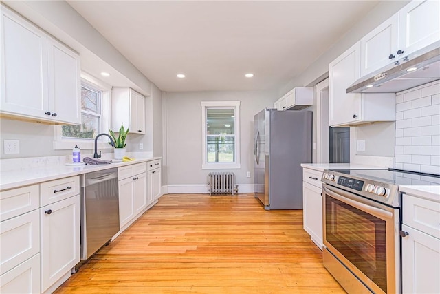888 Providence St, West Warwick, RI 02893 - kitchen with radiator, under cabinet range hood, a sink, a wealth of natural light, and stainless steel appliances