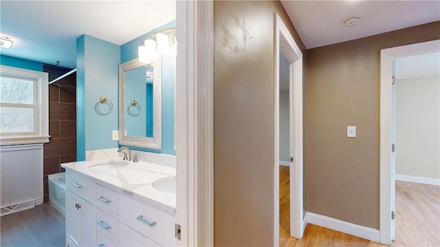 108 Shady Lea Rd, North Kingstown, RI 02852 - full bathroom with double vanity, wood finished floors, a sink, baseboards, and washtub / shower combination