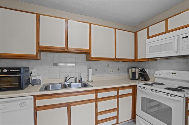 kitchen featuring decorative backsplash, a sink, light countertops, white appliances, and white cabinetry