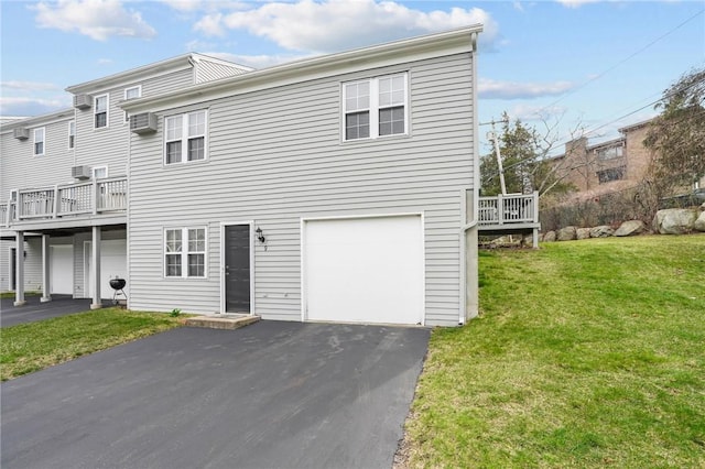 multi unit property with a garage, a front lawn, a deck, a wall mounted air conditioner, and driveway