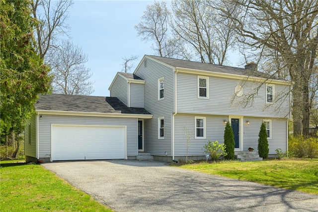 colonial home with driveway, a chimney, a front yard, an attached garage, and entry steps