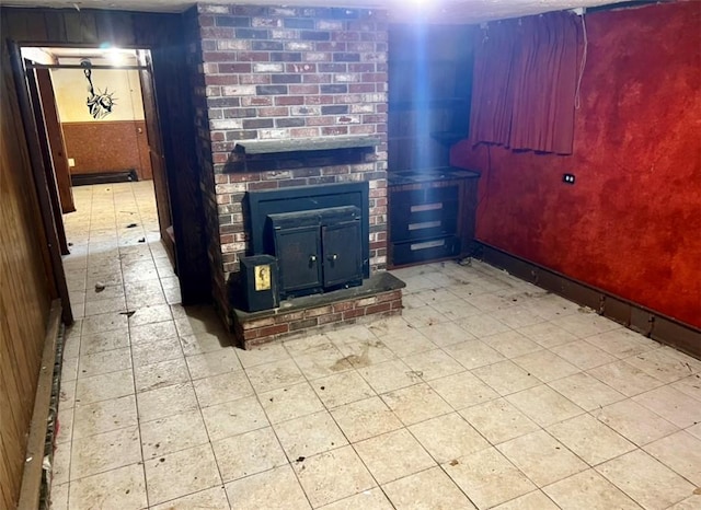 unfurnished living room featuring wooden walls, tile patterned floors, and baseboards