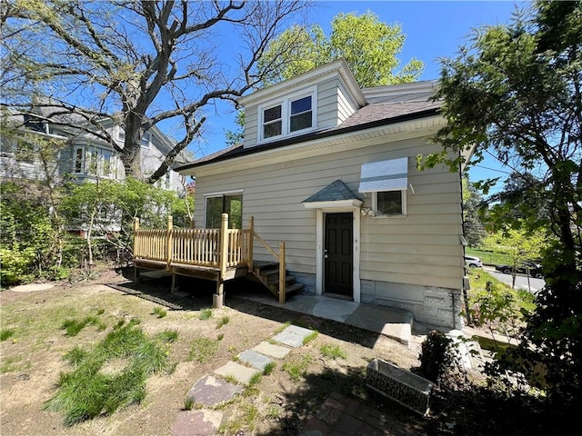 rear view of property with a wooden deck and a shingled roof
