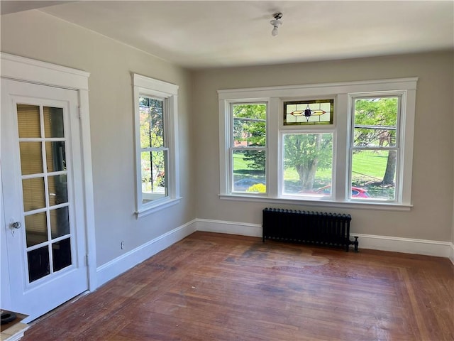 unfurnished room featuring baseboards, radiator, and wood finished floors
