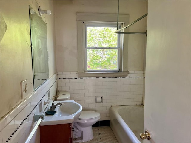 full bathroom with vanity, toilet, a wainscoted wall, a tub, and tile walls