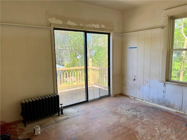 unfurnished room featuring radiator heating unit and wood walls