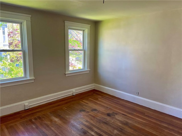 empty room featuring baseboards and dark wood finished floors