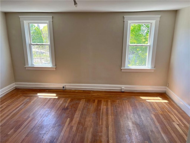spare room with wood-type flooring and baseboards