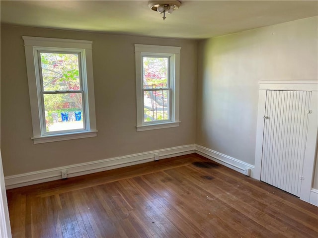 unfurnished room with a healthy amount of sunlight, baseboards, and hardwood / wood-style floors