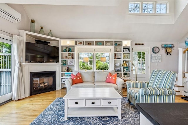 living area with a wall mounted air conditioner, wood finished floors, and a healthy amount of sunlight