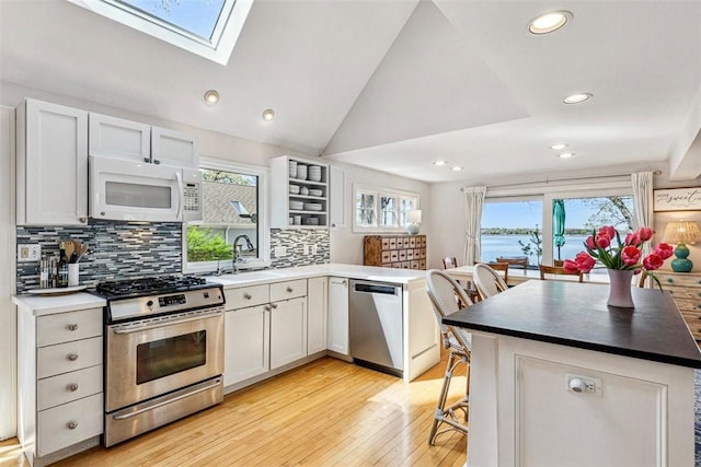 kitchen with a sink, light wood-style floors, stainless steel appliances, recessed lighting, and decorative backsplash
