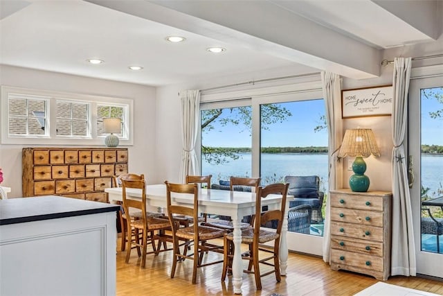 dining room with recessed lighting, plenty of natural light, light wood-style flooring, and a water view