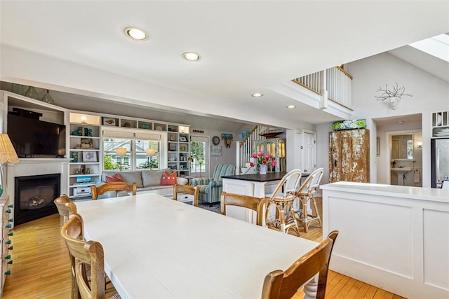 dining space featuring a fireplace, light wood finished floors, and recessed lighting
