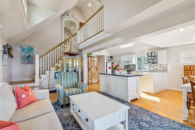living room featuring stairs, recessed lighting, a baseboard heating unit, and light wood-type flooring