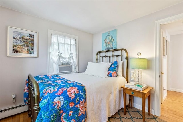 bedroom with baseboards, cooling unit, wood finished floors, and a baseboard radiator