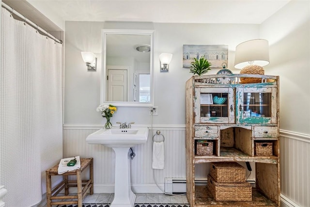 bathroom featuring curtained shower, a sink, a wainscoted wall, tile patterned floors, and a baseboard heating unit