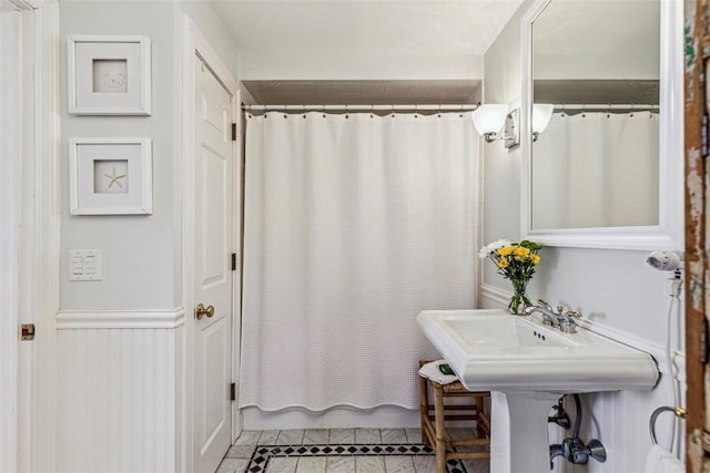 full bath featuring tile patterned floors and a wainscoted wall