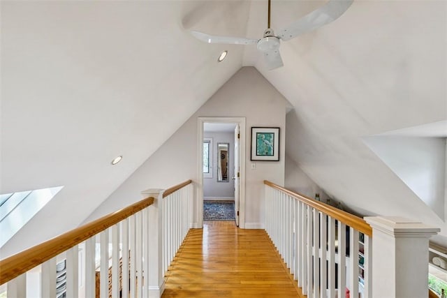 hall featuring vaulted ceiling with skylight, recessed lighting, light wood finished floors, and an upstairs landing
