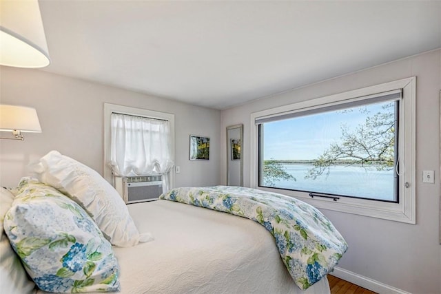 bedroom with baseboards, cooling unit, and wood finished floors