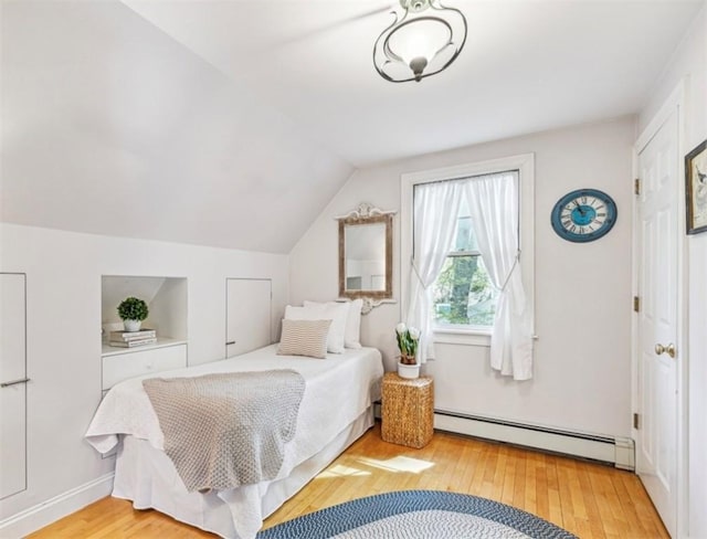 bedroom with a baseboard heating unit, wood finished floors, and lofted ceiling
