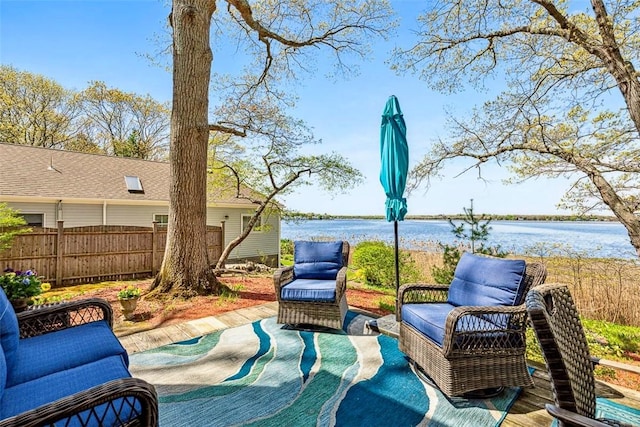 view of patio with fence and a water view