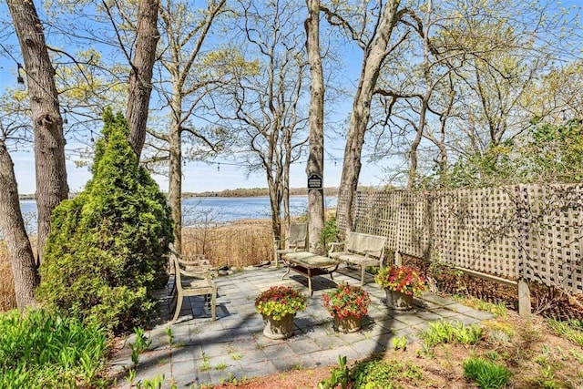 view of yard featuring a water view, a patio area, and fence
