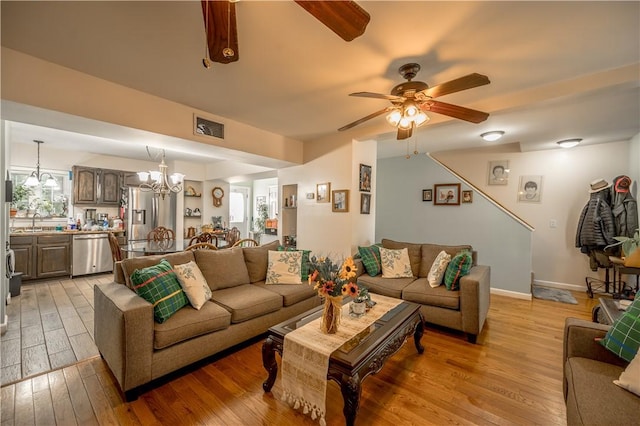 living area featuring visible vents, ceiling fan with notable chandelier, and light wood-type flooring