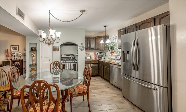 kitchen with dark brown cabinetry, a chandelier, stainless steel appliances, visible vents, and pendant lighting