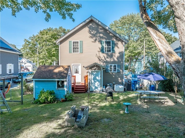 back of property with a storage unit, a yard, an outbuilding, and fence
