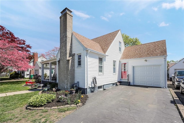 view of property exterior featuring a garage, a chimney, driveway, and roof with shingles