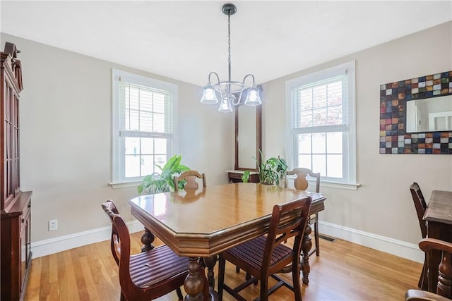 dining space featuring light wood-style floors, baseboards, and a notable chandelier