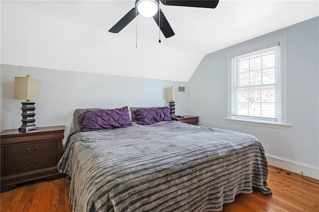 bedroom with a ceiling fan, vaulted ceiling, wood finished floors, and visible vents