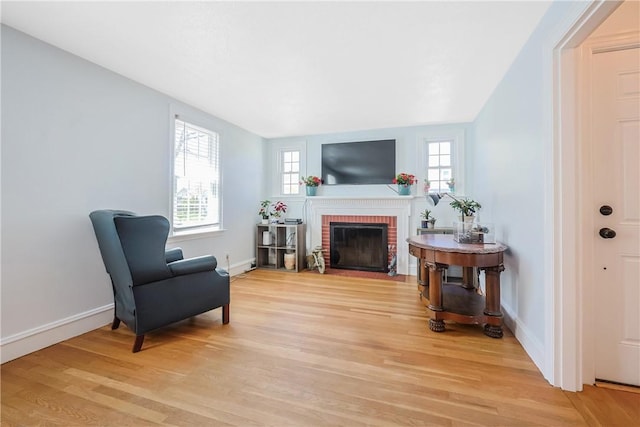 living area with light wood-type flooring, baseboards, a wealth of natural light, and a fireplace