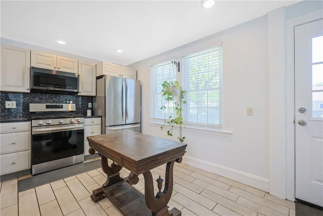kitchen featuring dark countertops, baseboards, recessed lighting, appliances with stainless steel finishes, and backsplash