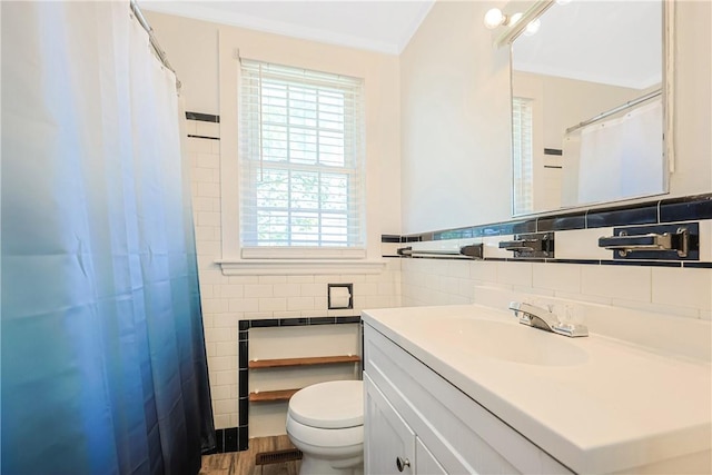 full bath featuring tile walls, wood finished floors, vanity, toilet, and ornamental molding
