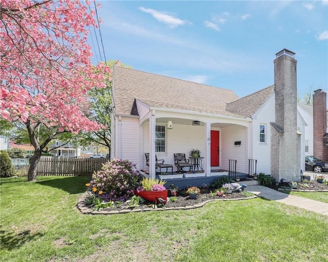 bungalow-style home with fence, a chimney, a porch, and a front lawn