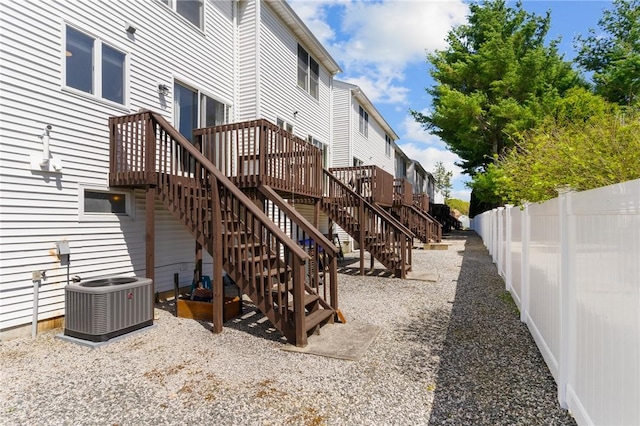 exterior space with a wooden deck, fence private yard, central AC, and stairway