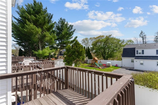 deck featuring a storage unit, an outdoor structure, a playground, and a fenced backyard
