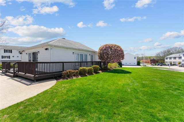 view of home's exterior featuring a lawn, a wooden deck, a shingled roof, and french doors