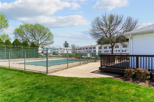 view of basketball court with fence and a yard