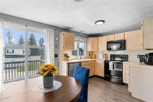 kitchen with backsplash, a sink, light countertops, black appliances, and light brown cabinets
