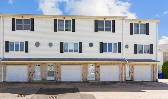 townhome / multi-family property with brick siding and a garage