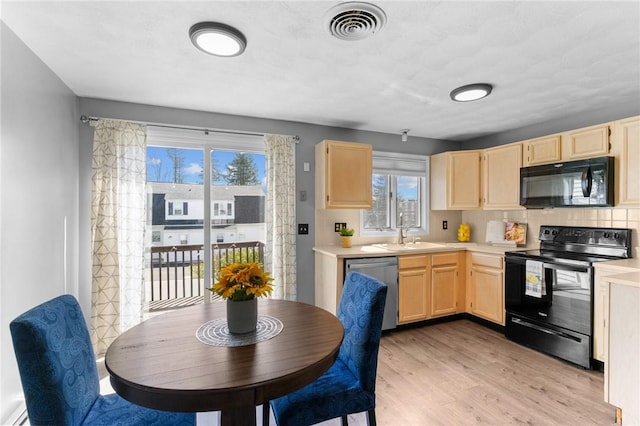 kitchen featuring visible vents, light brown cabinets, light countertops, a sink, and black appliances