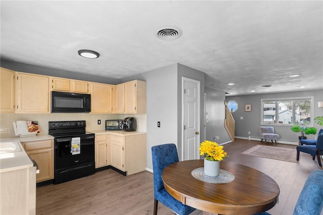 kitchen featuring visible vents, light brown cabinets, light wood-style floors, light countertops, and black appliances
