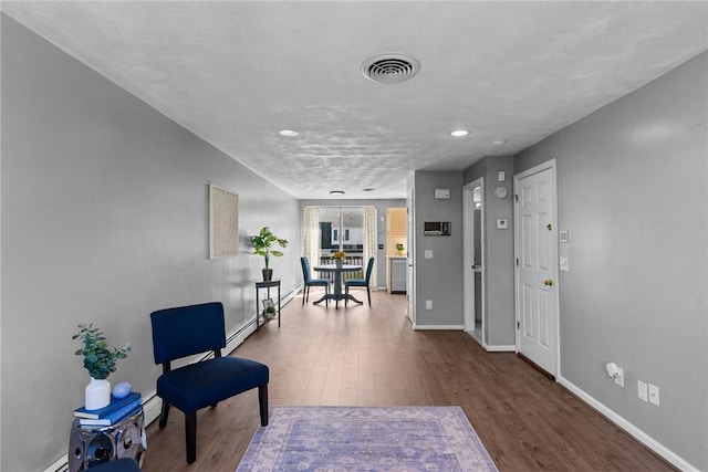interior space with visible vents, wood finished floors, baseboards, a baseboard radiator, and a baseboard heating unit