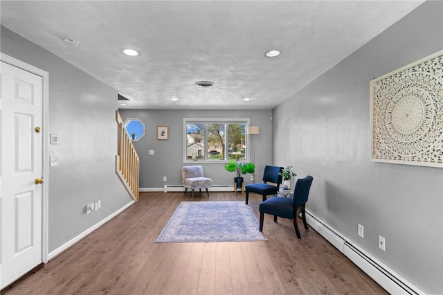 living area with recessed lighting, a baseboard radiator, stairs, and wood finished floors