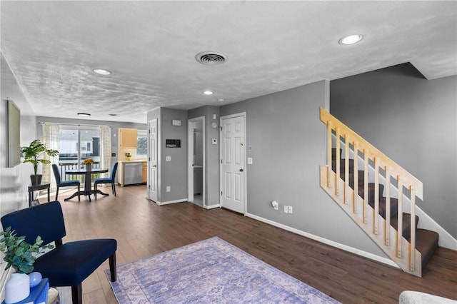 living area with stairway, baseboards, wood finished floors, and visible vents